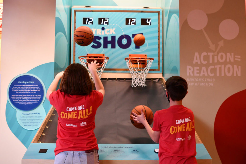 Image of children shooting basketballs in Science City's "Step Right Up" Exhibit. Indoor fun activities like these are all over Science City.