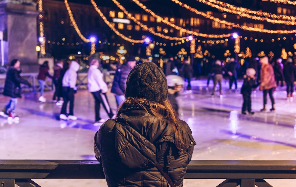 woman watching over an ice skating rink at night during holiday events in Kansas City